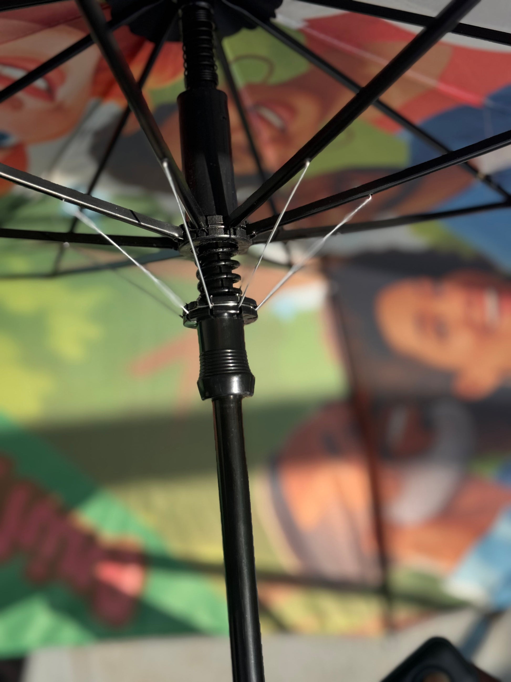 Close-up of an umbrella's black shaft and metal spokes against a colorful background
